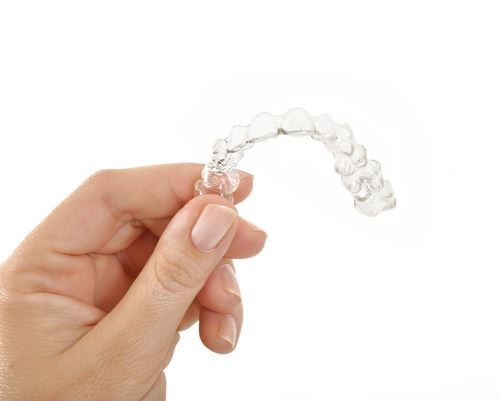 Hand holding Invisalign aligner